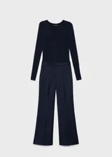 Mono largo de diseño combinado, con parte superior de tejido de punto acanalado con cuello en pico y cierre frontal de botones, y parte inferior de pantalón de corte recto. Cuenta con manga larga y bolsillos laterales.