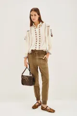 Pantalón tipo babucha de gabardina elastizada, color negro, con cintura elástica ajustable mediante cordón, puños en los tobillos, bolsillos diagonales frontales y bolsillos traseros con solapa y botón.