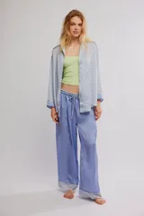 Conjunto de pijama de dos piezas, compuesto por una camisa de manga larga con estampado geométrico, cuello y botonadura frontal, y un pantalón largo fluido de color celeste con cintura elastizada, cordón de ajuste y detalles estampados en los dobladillos.