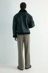Pantalón de corte relajado y pierna recta, confeccionado en tejido suave de color marrón. Presenta cintura elástica con cordón de ajuste, pliegues frontales y traseros, bolsillos laterales y un bolsillo posterior insertado.