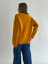 Sweater de punto con textura tipo waffle, color mostaza, de corte holgado, cuello redondo y mangas largas con puños acanalados.