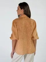 Camisa de lino color beige, con mangas abullonadas tres cuartos y cierre frontal de botones.