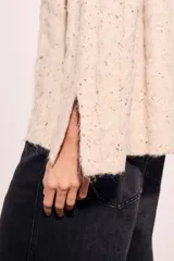 Sweater color crema con cuello alto, tejido de punto con textura y mangas largas con puños acampanados.