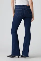 Jean de corte flare con tiro alto, confeccionado en denim azul oscuro con efecto desgastado. Presenta cierre de cremallera con botón metálico, cinco bolsillos tradicionales y costuras reforzadas.