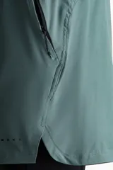 Short deportivo de doble capa color verde con calzas cortas negras incorporadas en el interior. Cuenta con tecnología DryMove™, cintura elástica negra con cordón ajustable, bolsillos laterales y aberturas en el bajo.