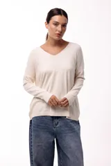 Sweater de punto color manteca, con cuello en V, manga larga y diseño holgado.