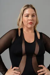 Body negro de lycra y microtul, con manga larga, cortes en los hombros y broches en la entrepierna.