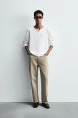 Camiseta de manga larga blanca, corte relajado, con cuello redondo y tapeta de botones (cuello panadero o henley).