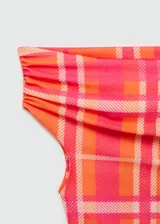 Top corto de escote barco con diseño de hombros descubiertos, confeccionado en tejido elástico con estampado de cuadros en tonos naranja y fucsia.