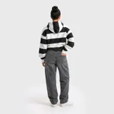 Hoodie de corte holgado con diseño de rayas horizontales anchas en blanco y negro. Presenta una capucha integrada y un bolsillo frontal tipo canguro. En el pecho, destaca un estampado gráfico con el texto 'eneroclub' en letras rojas con contorno blanco.