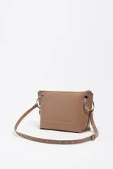 Bolso bandolera de estructura rígida y tamaño mediano confeccionado en piel vacuna. Presenta asa regulable, cierre con cremallera, bolsillo interior y logo metálico de la marca. Incluye un charm decorativo con borlas en el lateral y acabados metálicos.