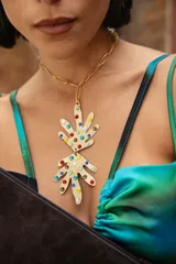 Collar de cadena de eslabones dorados con un dije grande de metal en forma de mano estilizada, decorado con cristales de colores tipo hotfix.