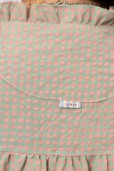Camisa amplia de manga corta con estampa a cuadros en tonos verde y rosado, cuello con volados y cierre frontal con botones.