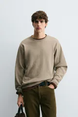 Sudadera de cuello redondo con ajuste regular, confeccionada en tejido de mezcla de algodón con interior de rizo y acabados en rib en cuello, puños y ruedo.