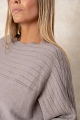 Buzo de punto color azul petróleo, con cuello redondo, mangas largas con puños ajustados y detalles de textura trenzada en la parte superior y el ruedo.