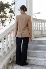 Blazer color camel de corte clásico, con solapas de muesca, doble botonadura y bolsillos delanteros con solapa.