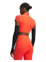 Top deportivo de entrenamiento Under Armour, modelo Vanish Elite, color naranja neón. Presenta un diseño cropped con cuello alto y cierre frontal parcial, mangas cortas raglán con paneles de malla para mayor ventilación y tejido elástico de secado rápido.