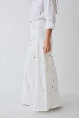 Pantalon de corte wide leg y tiro alto, confeccionado en tela con estampado deportivo que incluye pelotas de futbol y raquetas de tenis en tonos verde, rosa y beige.