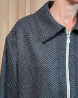 Chaqueta de textura bouclé en color bordó, con corte oversize, cuello camisero, cierre frontal y bolsillos laterales.