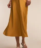 Pollera midi evasé de color beige claro, confeccionada en tela satinada de poliéster.