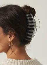 Broche para el cabello tipo pinza, de diseño translúcido en color gris humo con acabado brillante y mecanismo de resorte metálico.