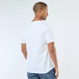 Camiseta blanca de manga corta con estampado frontal de la icónica lengua y labios de The Rolling Stones rodeada de llamas, con una cinta que dice "Tattoo You" y el nombre de la banda en tipografía manuscrita.