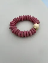 Set de tres pulseras elásticas con cuentas de madera en colores celeste, negro y rosa, con detalles de cuentas doradas y cuentas color crema.
