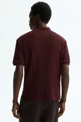 Remera polo de punto texturizado color bordó, de manga corta, con cuello y tapeta de dos botones. Corte ajustado slim fit.