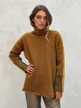 Sweater de punto con patrón de espiga en tonos beige y marrón, cuello alto, mangas largas con detalles en naranja y puños marrones.