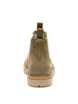 Bota tipo Chelsea de Caterpillar, confeccionada en gamuza color tostado con paneles elásticos laterales en color verde oliva. Presenta suela de goma dentada y tiradores en la parte superior trasera.