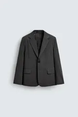 Blazer oversized fit de hombre, color gris oscuro con rayas verticales finas. Cuello con solapas de muesca, manga larga con puño abotonado, bolsillos de solapa en la cadera y bolsillo interior. Cierre frontal de un botón y abertura en el centro de la espalda.