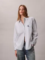 Camisa de Calvin Klein color celeste con patrón de rayas verticales finas y logo 'ck' bordado en el bolsillo frontal. Presenta cuello camisero, cierre frontal con botones y manga larga.