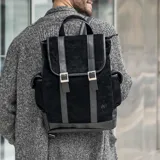 Mochila negra de cuero vacuno con bolsillo con broche a presión a cada costado y bolsillo con cierre en la parte trasera. Tiene cierre superior y tapa con broche a presión. El interior está forrado y contiene un bolsillo con cierre y otro pequeño para el móvil.
