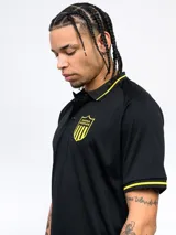 Remera polo negra de poliéster con cuello clásico y mangas cortas. Presenta ribete amarillo en cuello y mangas, escudo del Club Atlético Peñarol bordado en el pecho y corte regular.