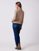 Buzo de tejido de punto color beige, con cuello alto y mangas largas. Presenta un diseño de calce ajustado con puños y ruedo acanalados.