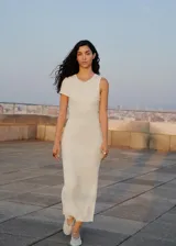 Vestido largo de punto acanalado en color blanco, con diseño entallado y cuello redondo. Presenta un estilo asimétrico en la parte superior con una manga corta y un hombro descubierto.