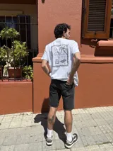Remera blanca de manga corta y cuello redondo, con gran estampado en la espalda de temática playera dentro de un marco decorativo.