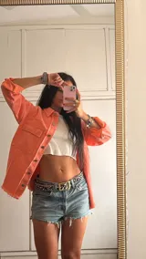 Sobrecamisa color coral con cuello camisero, cierre frontal con botones, dos bolsillos amplios en el pecho y terminaciones desflecadas.