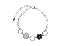 Pulsera de acero plateado con eslabones y dijes de flores esmaltadas en blanco y negro. Incluye cadena de alargue.