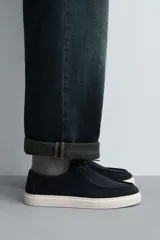 Zapato casual de hombre, color beige claro, con capellada de serraje (gamuza) y cordones finos. Presenta un detalle de bordón en el empeine y suela gruesa de goma a contraste en color crema.