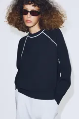 Jersey de punto de manga larga con cuello redondo, diseño en color azul marino con detalles de vivo en color blanco en el cuello y las costuras de las mangas.
