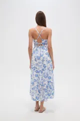 Vestido largo de viscosa, estampado en tonos blanco y azul con diseño floral tipo cachemir. Presenta escote en V, tirantes finos, talle ajustado con cordón y abertura lateral en la falda.