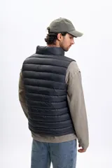 Chaleco capitoneado negro con cierre frontal, cuello alto y bolsillos laterales.