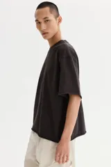 Remera boxy de algodón en punto liviano, de color negro, con hombros caídos, cuello redondo acanalado y corte oversized.