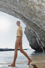 Polo de punto de manga corta con diseño a rayas horizontales en tonos amarillo claro y naranja, cuello camisero y cierre frontal de botones.