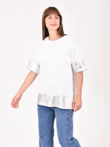 Remera blanca de corte holgado con detalles metalizados en color dorado en las mangas y el ruedo. Presenta un estampado minimalista con texto en el frente.