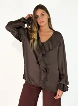 Blusa de satén color marrón chocolate, con escote en V y detalle de volados frontales. Presenta mangas largas con puños acampanados y volados.