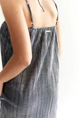 Vestido corto de corte recto, color azul oscuro con efecto metalizado y textura plisada vertical. Posee breteles finos ajustables y escote con elástico fruncido.