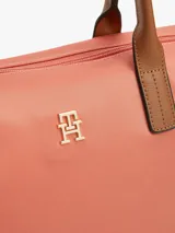 Cartera tote Tommy Hilfiger de nailon color salmón, con dos asas superiores de cuero sintético marrón y correa tejida extraíble. Cuenta con cierre de cremallera y detalle del monograma TH en metal dorado en la parte delantera.