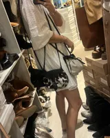 Bandolera negra de cuero gamuzado con solapa de cuero liso y cierre con tira de cuero.